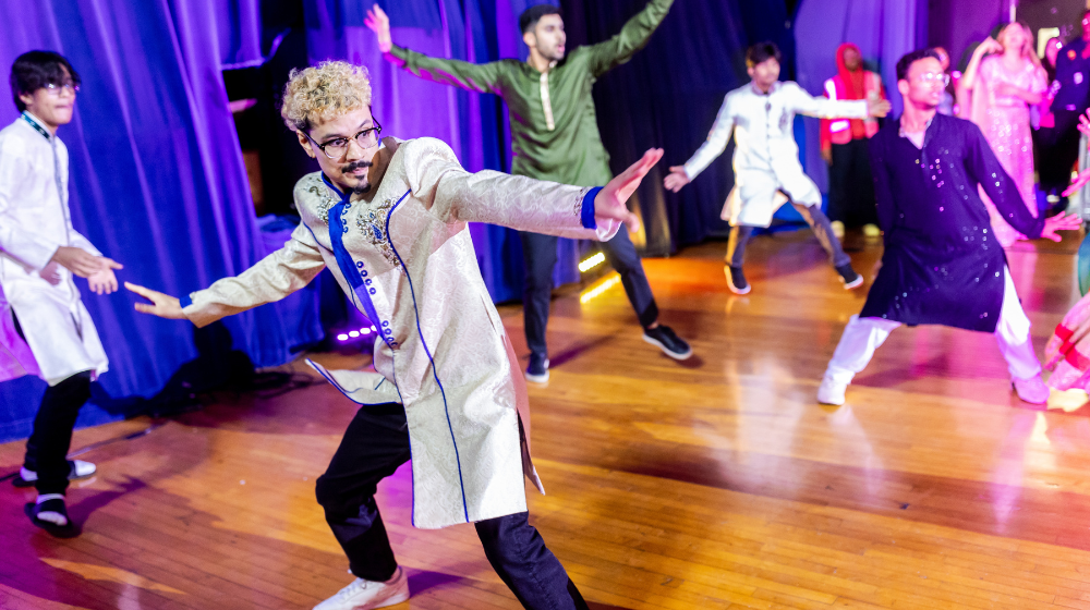 Photo of alumnus Joshua Zepeda performing on stage with students